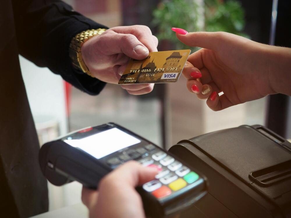 Close-up of a person using a credit card for a contactless payment at a card reader.