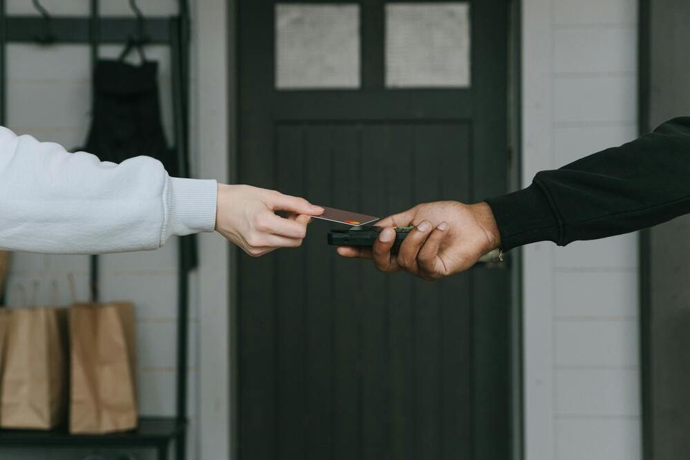 Two people exchanging a credit card with a dark door in the background.