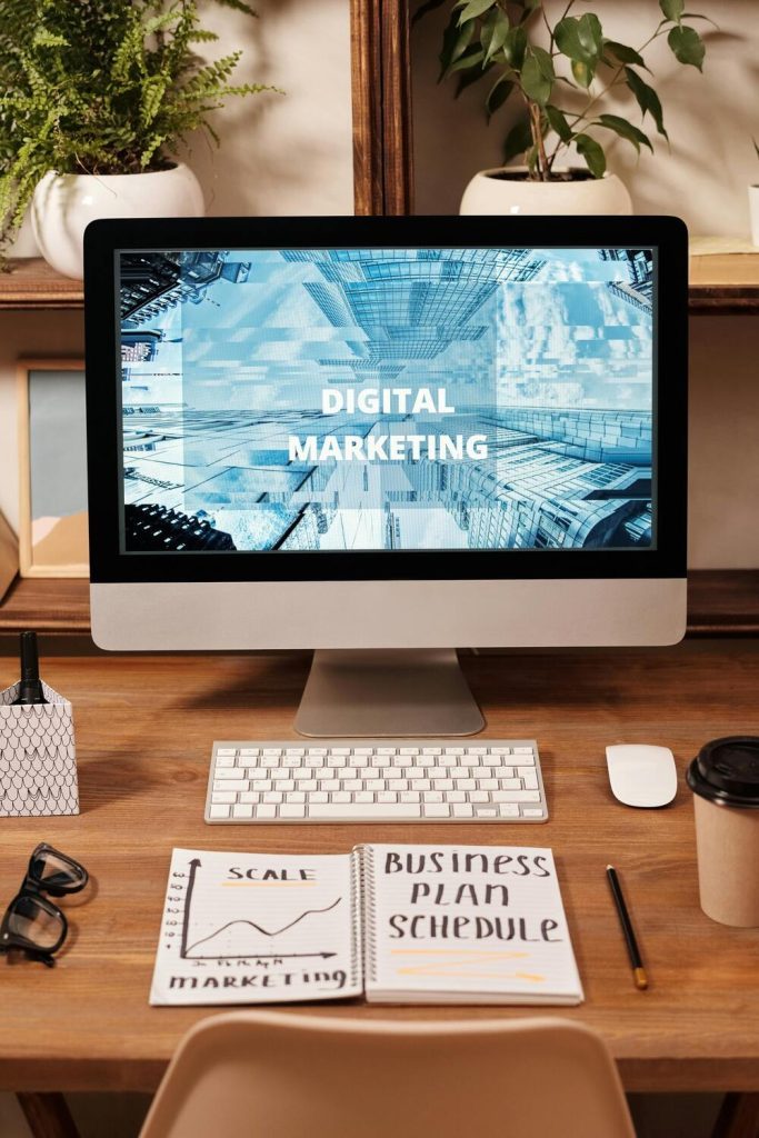 Workspace with computer screen displaying digital marketing, business plan, and desk items.