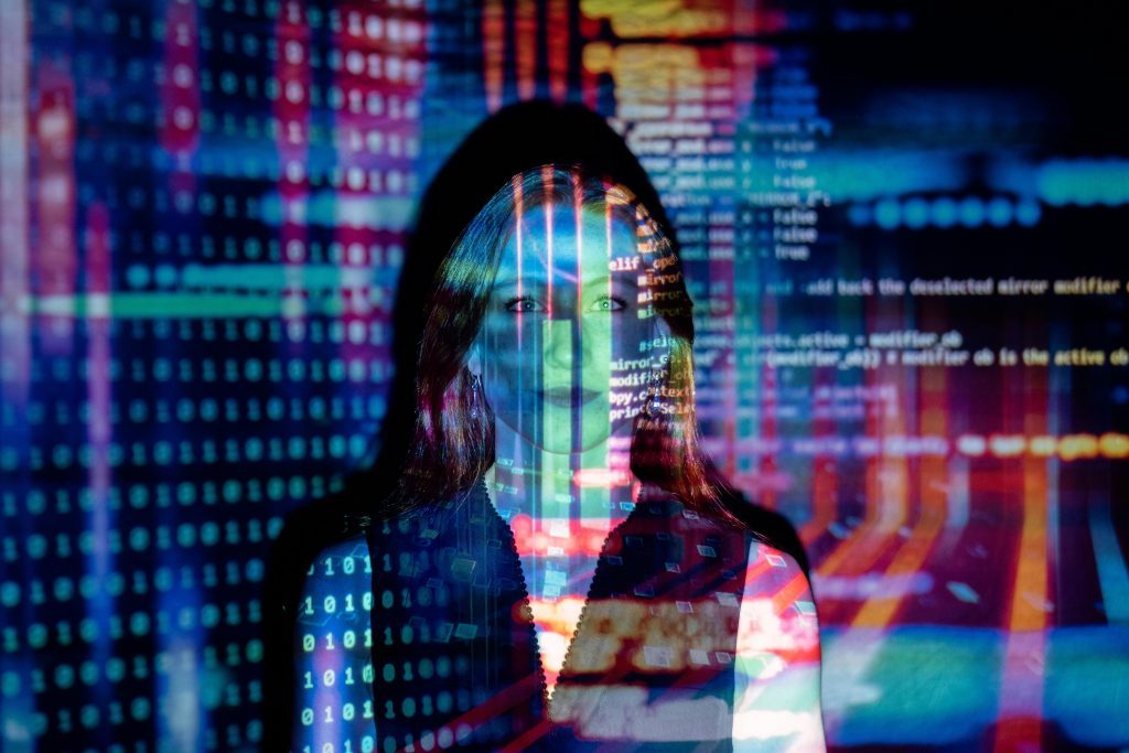 Woman's face superimposed with colorful computer code and data visualizations