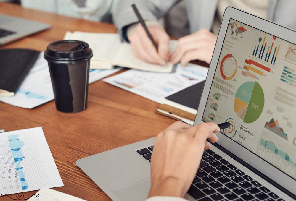 Professionals analyzing data charts and graphs on a laptop with coffee cup on desk.