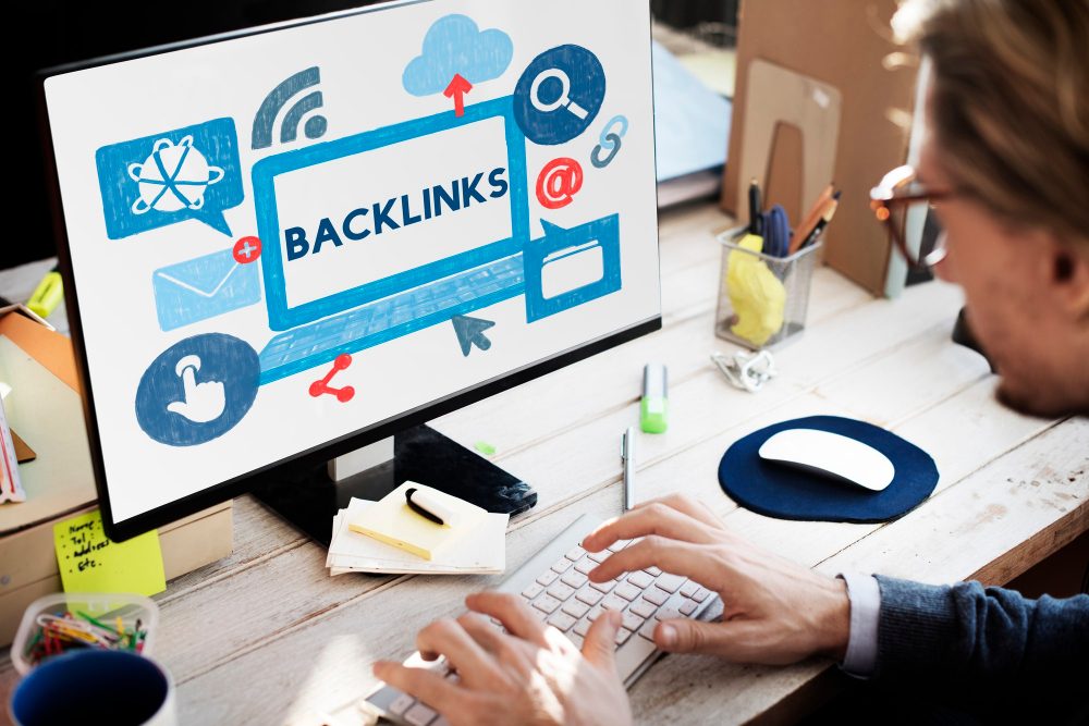 Person working at a desk with a computer screen displaying the word 'Backlinks' and various digital icons.